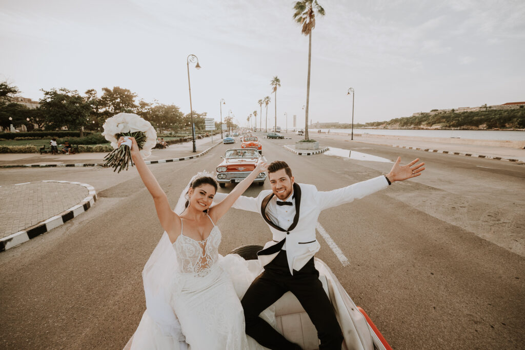 Novios pasean en auto antiguo descapotable por La Habana luego de su ceremonia de bodas. 